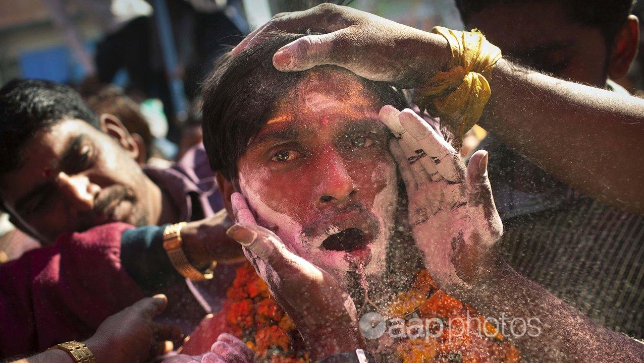 A Tamil Hindu priest having antiseptic powder rubbed on his face.