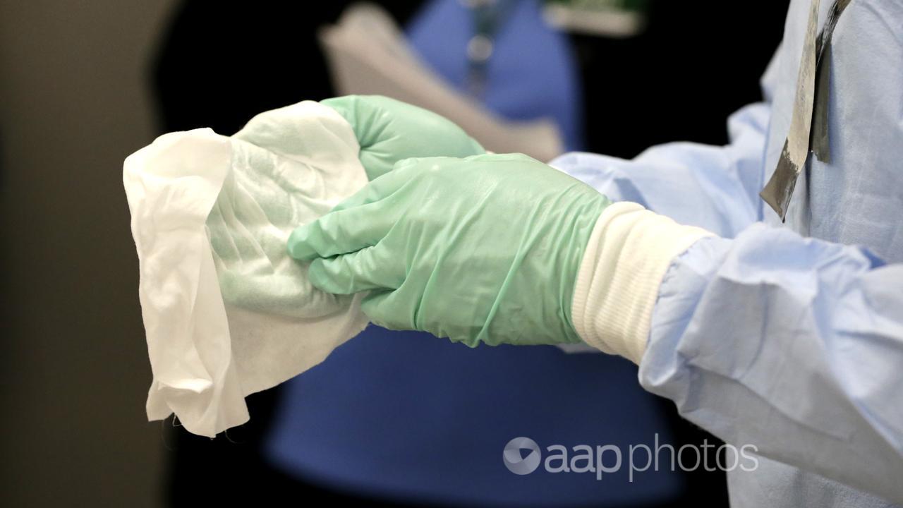 A nurse demonstrating how to clean surgical gloves using bleach.