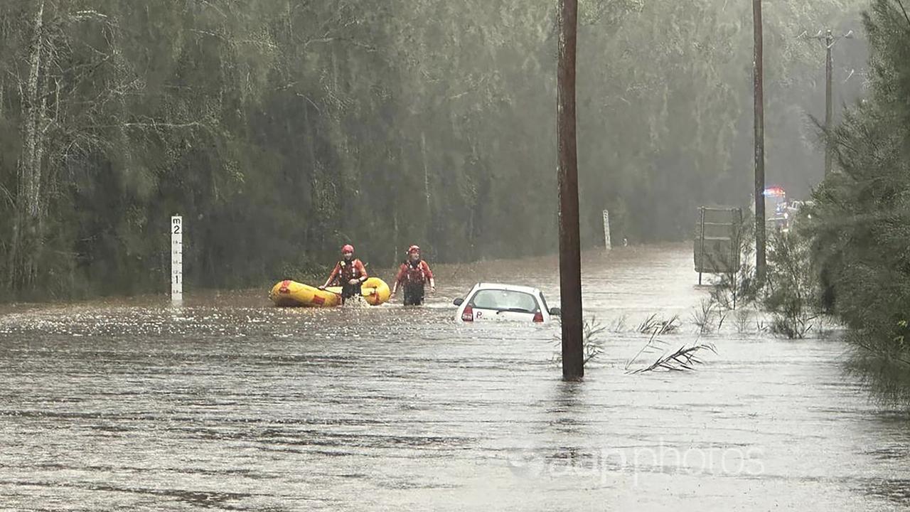 A rescue crew checks out a submerged car after heavy rains.