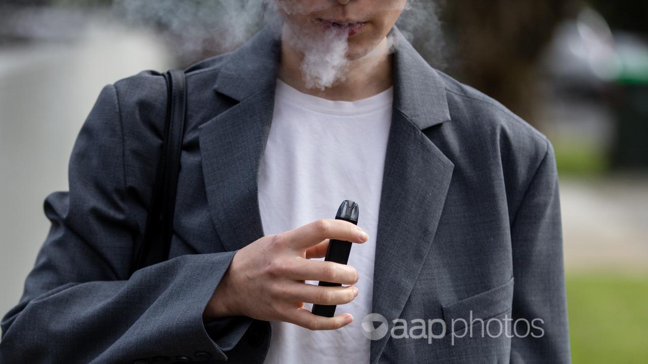 A woman smokes a vape.