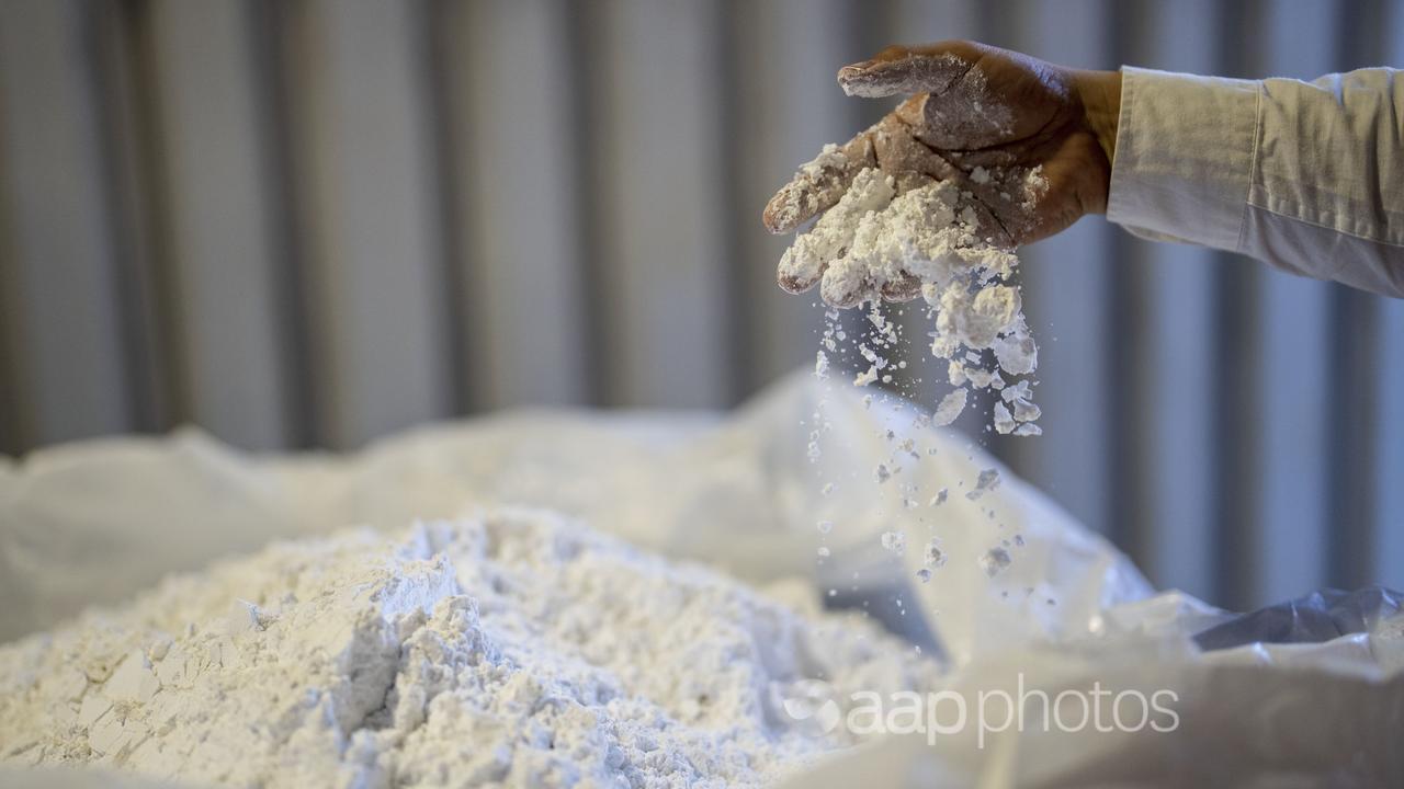 A worker stirs powdered lithium with his hand at  SQM processing plant