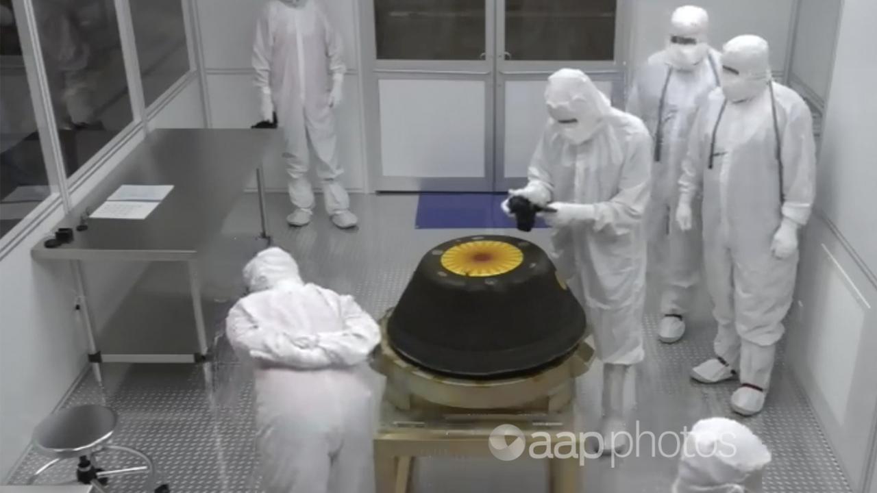 NASA technicians in a clean room examine the sample return capsule.