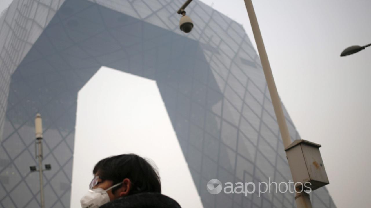 People in masks beside the China Central Television Tower, Beijing