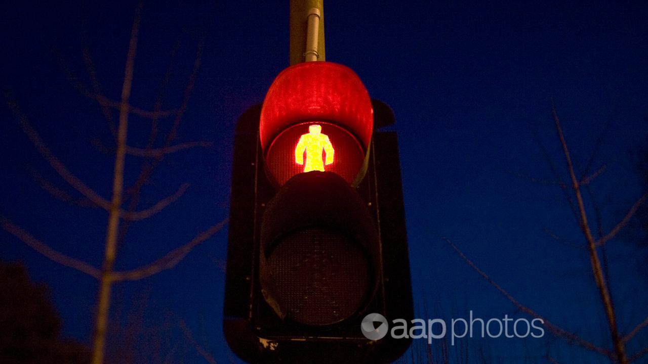 A traffic light illuminates a tree-lined street in Beijing, China