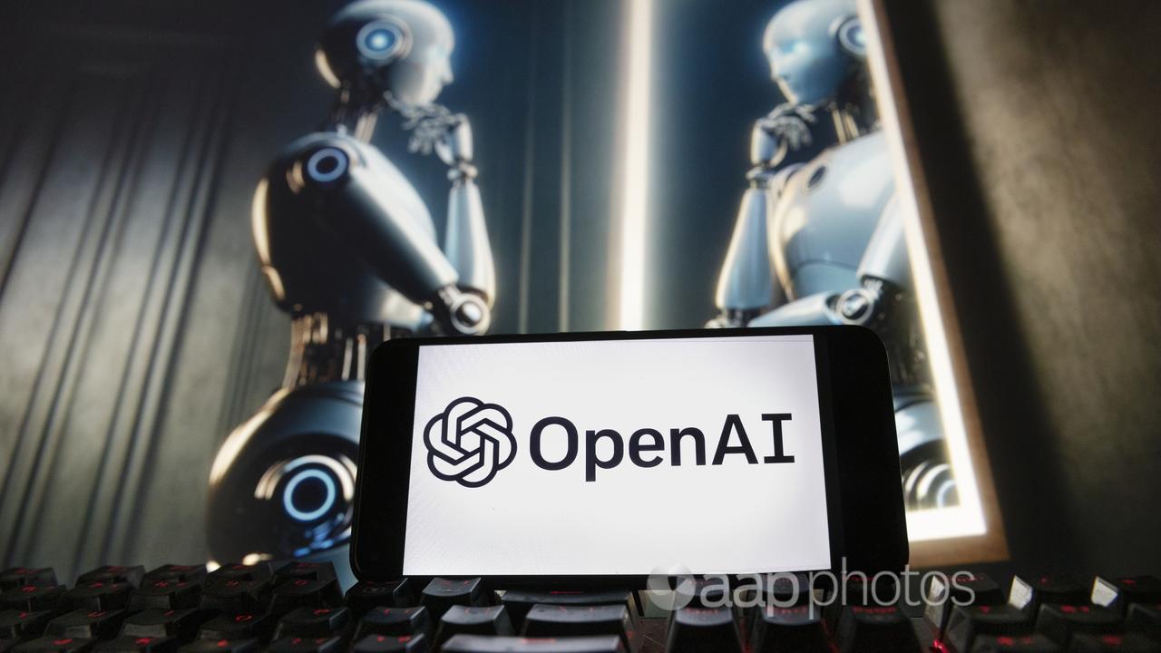 OpenAI logo on a phone with a robot image on a computer monitor