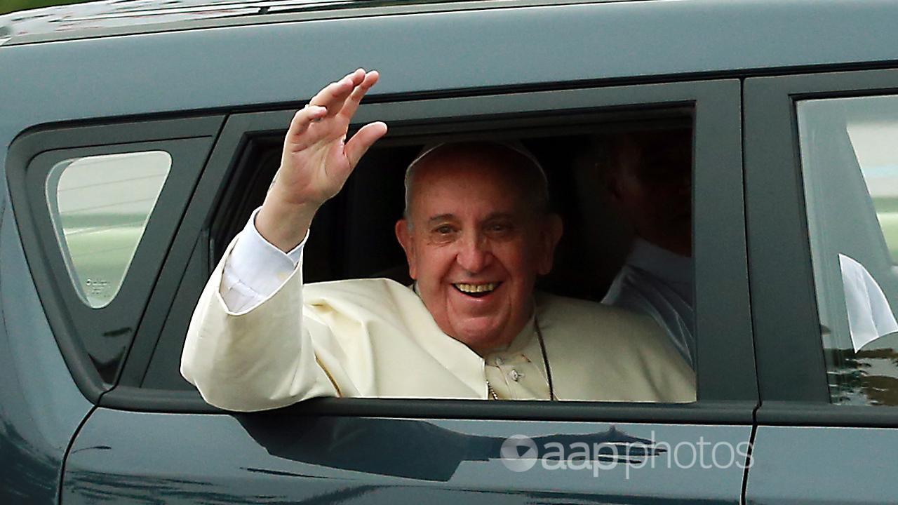 Pope Francis waves to well-wishers from a compact car