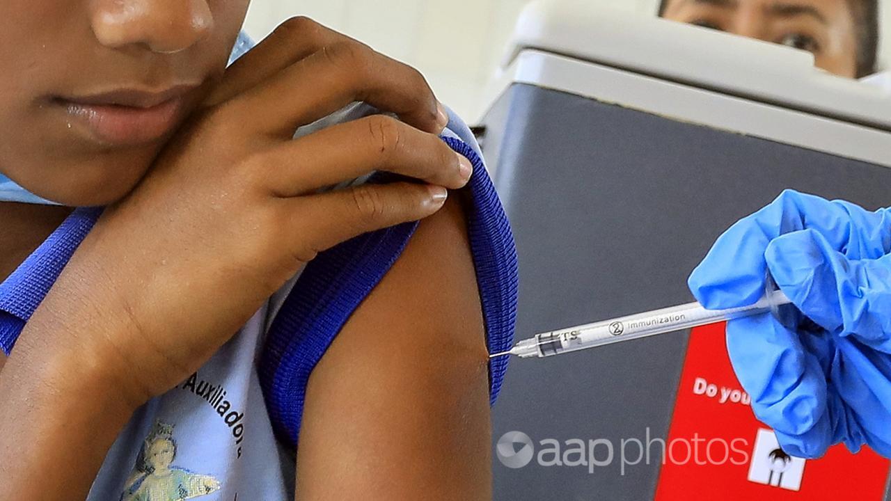 A child rolls up their arm to reeive the COVID vaccine.