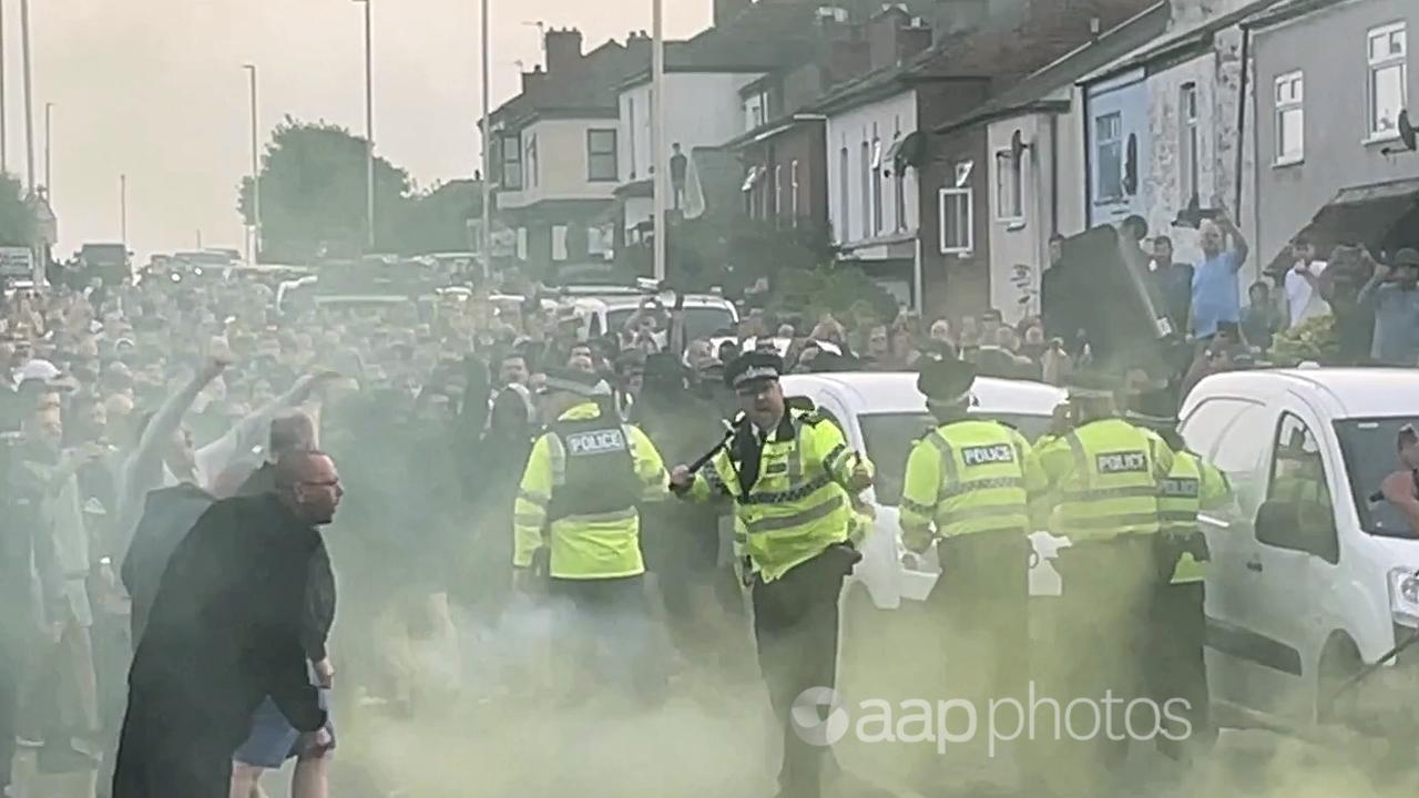 UK police officers attempt to hold the large crowd back.