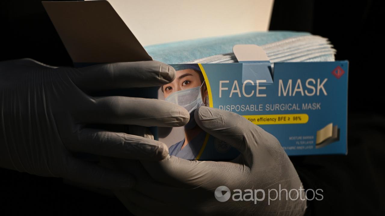 Two hands holding a box of surgical masks.