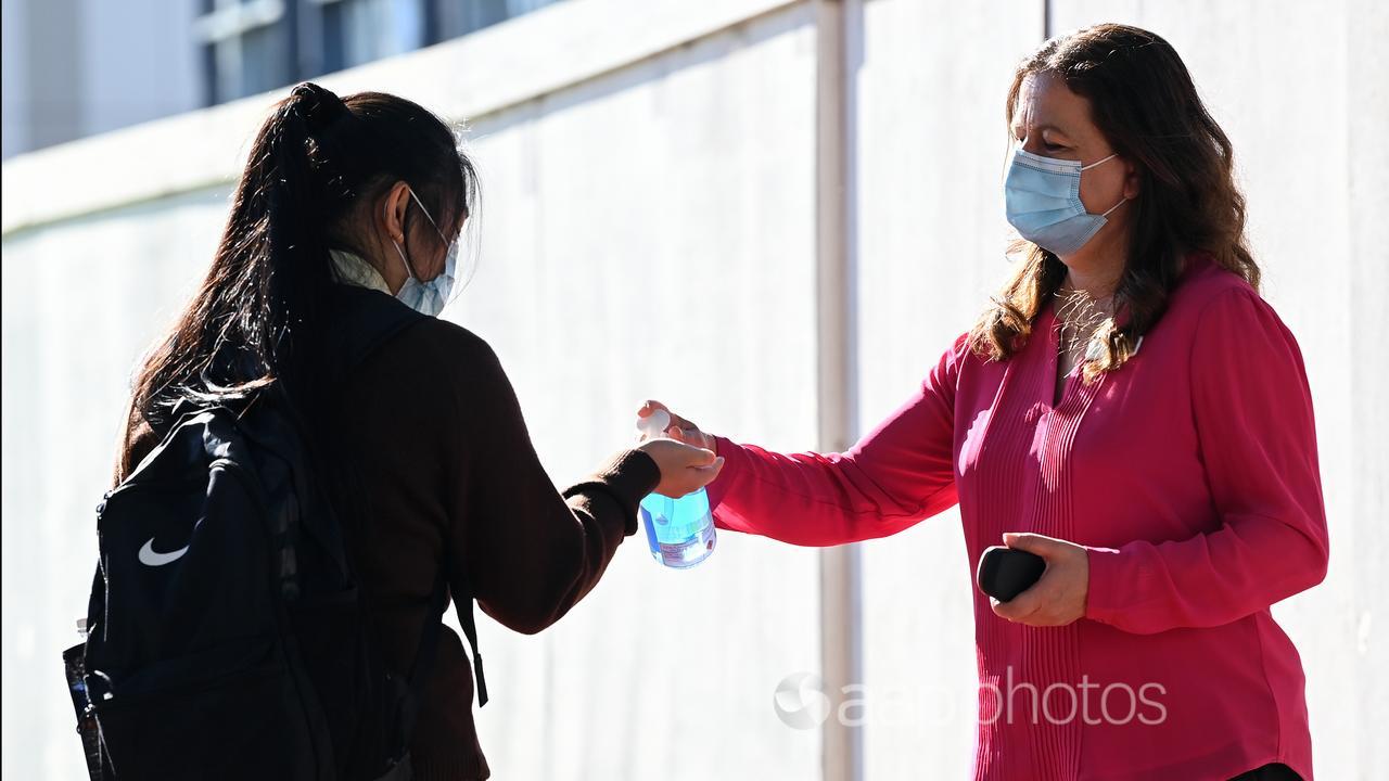 Hand sanitiser and face masks being provided to a student