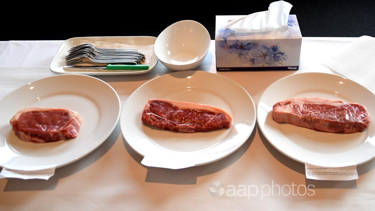 Four plates of beef lined up.