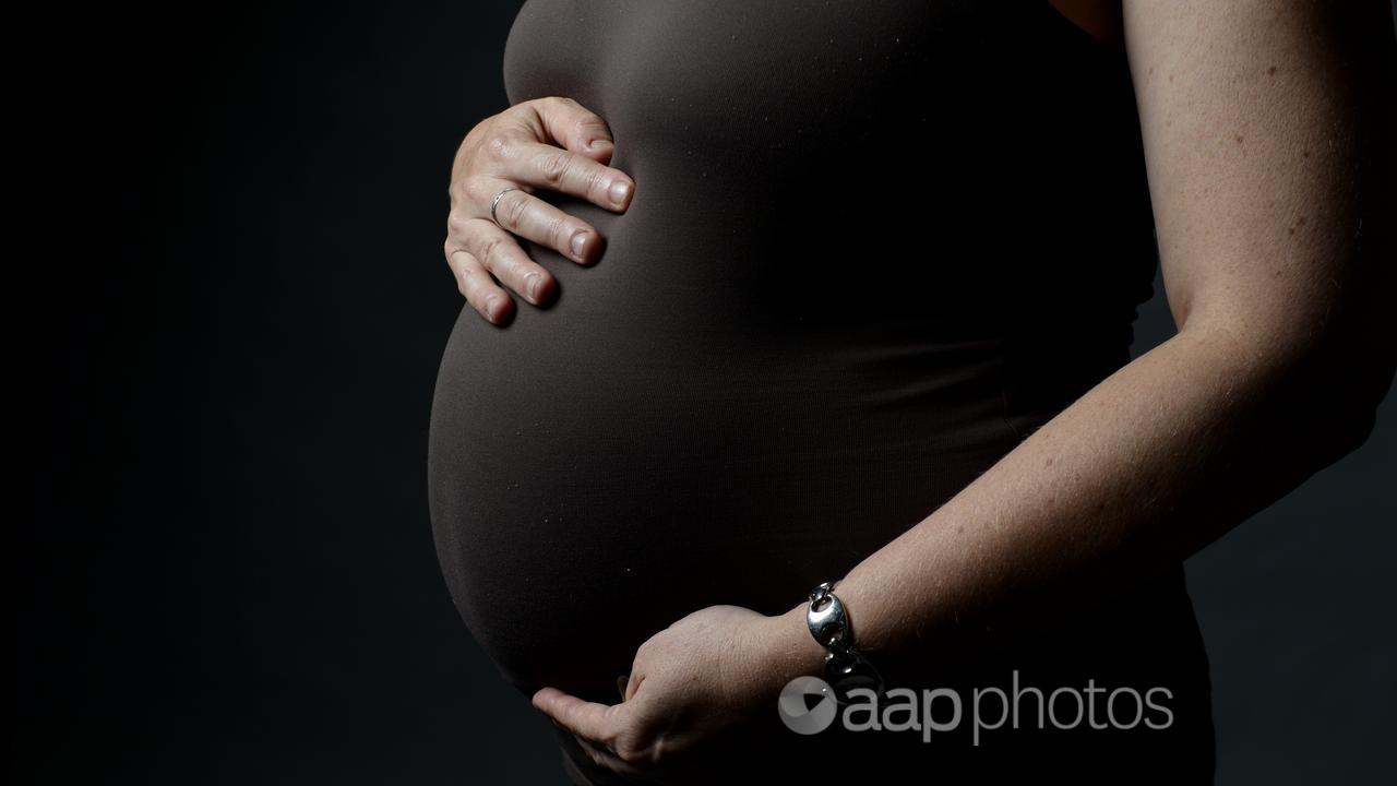 A pregnant woman holds her belly.