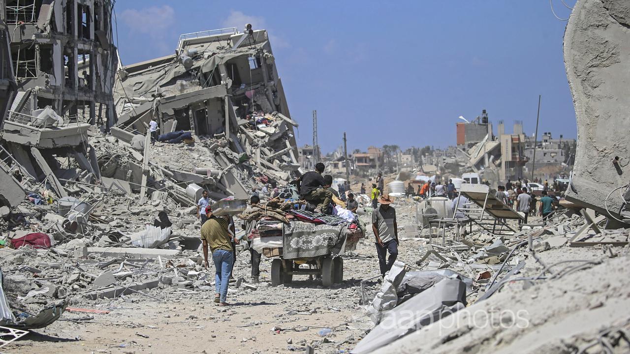 People stand among the rubble of buildings.