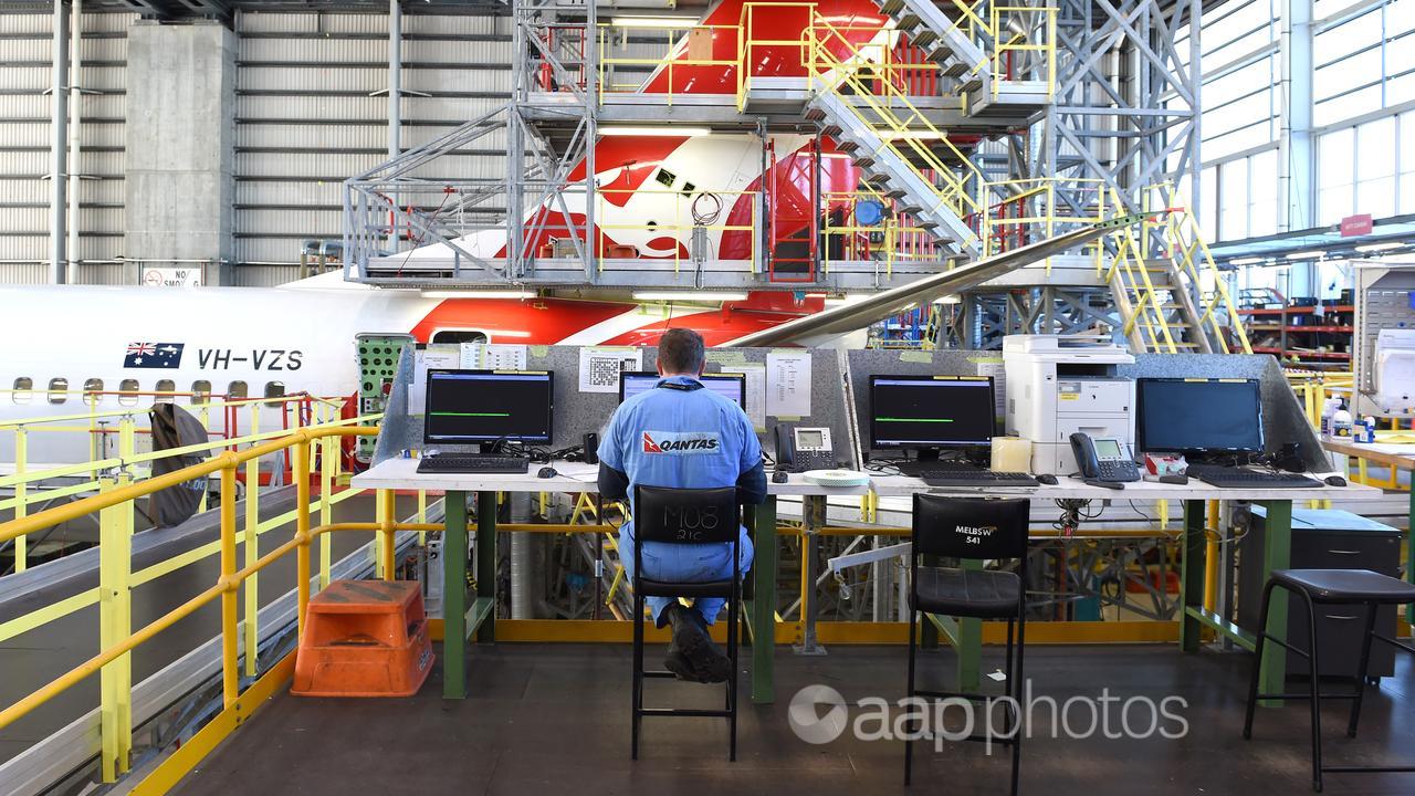 A Qantas employee seen as an aircraft receives maintenance