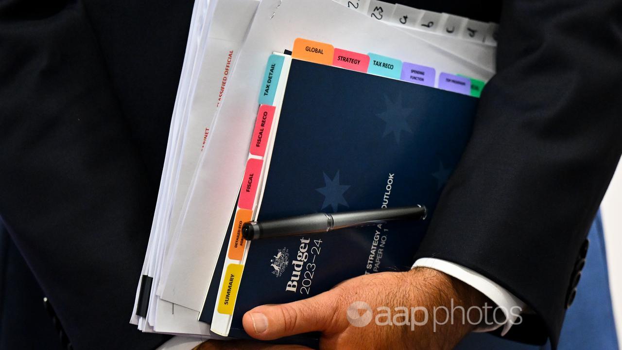 Treasurer Jim Chalmers holds a copy of the Budget papers