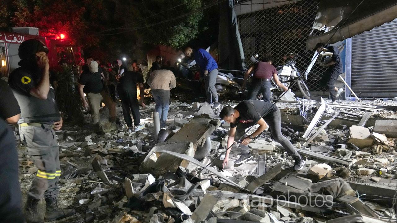 People work to clear debris after an airstrike in Beirut