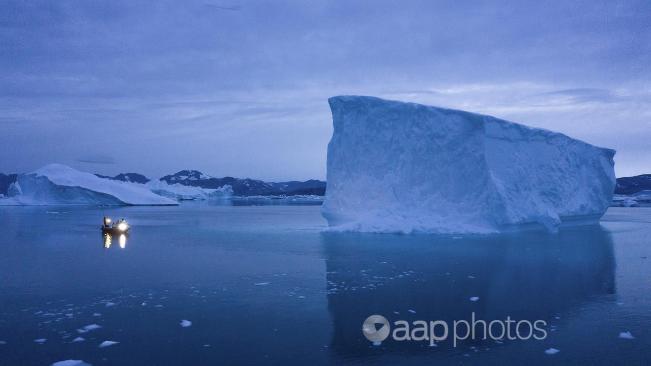 A boat next to large icebergs in Greenland.