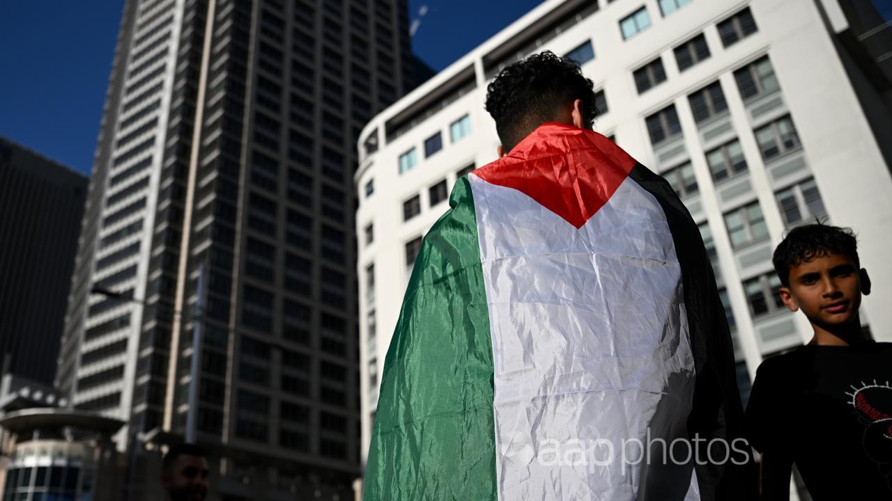 Person wears a Palestinian flag at a gathering in Sydney