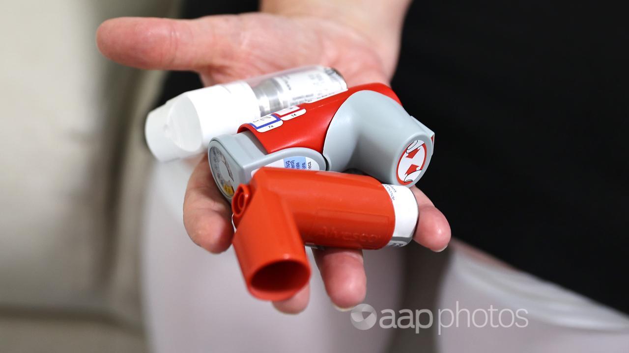 A hand holding asthma inhalers.