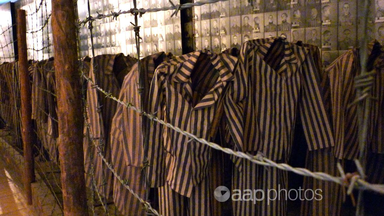 Uniforms left to images of victims at Auschwitz