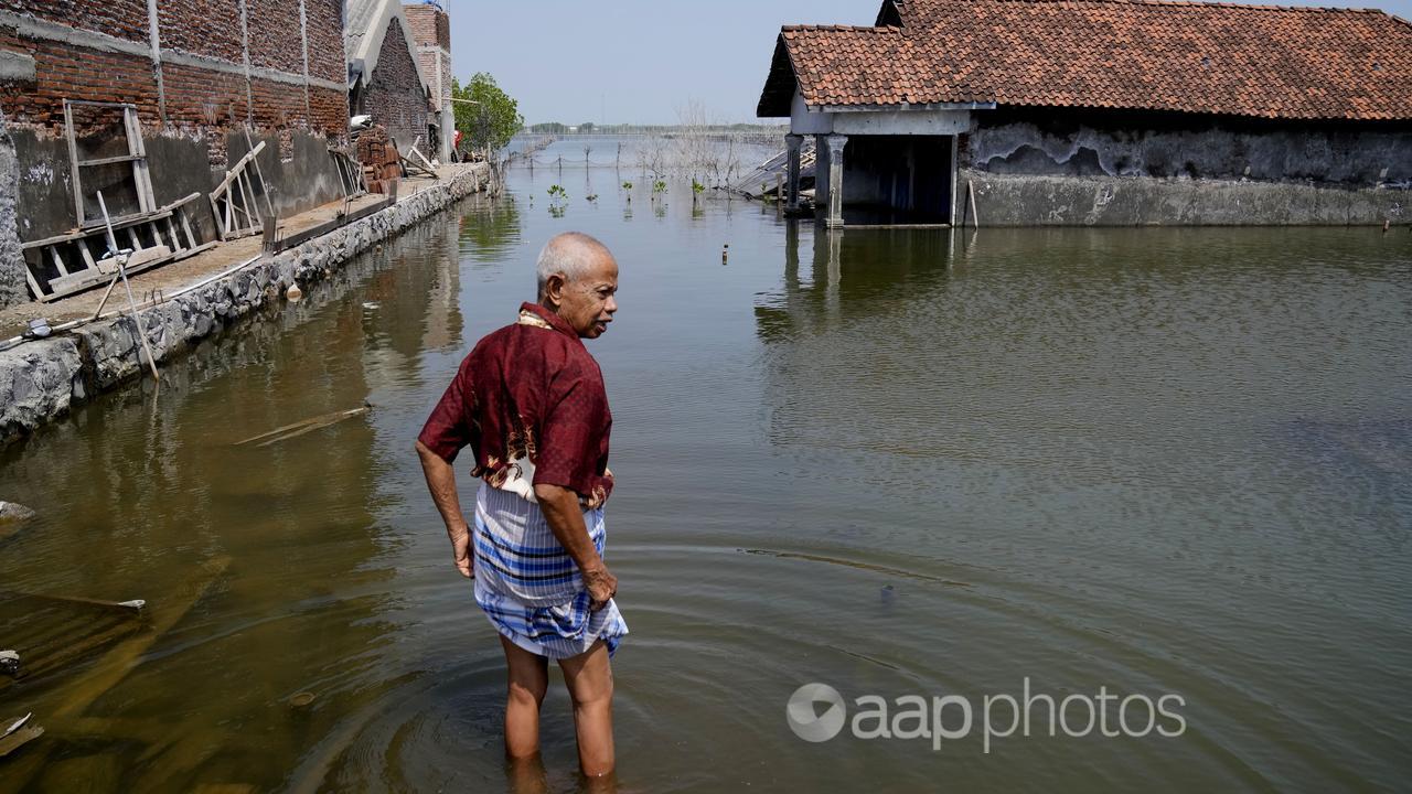 A man walks on a flooded pathway in Central Java.