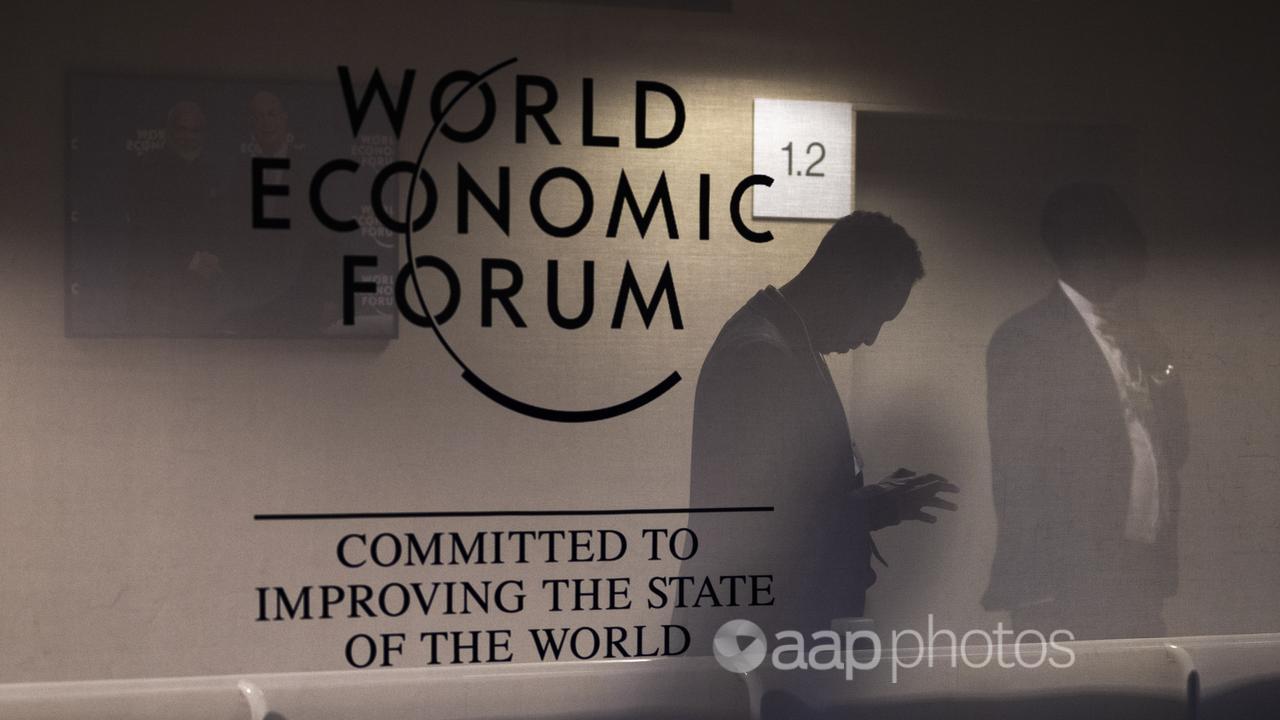 Men reflected in a panel with the WEF logo, Davos, Switzerland