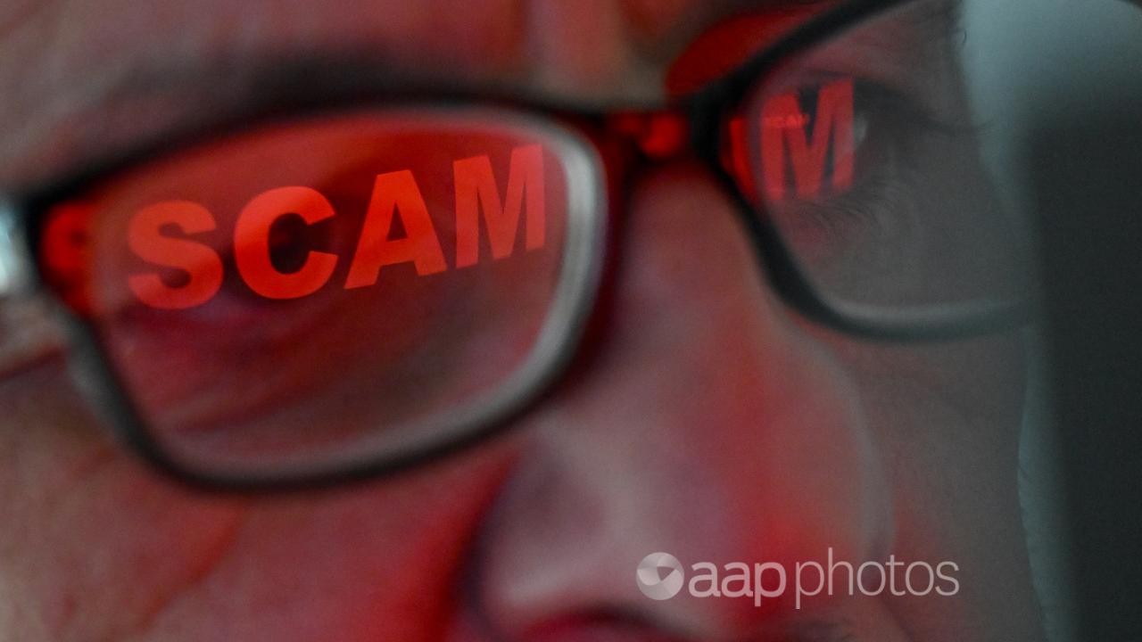 The word ‘scam’ reflected in a person’s glasses 